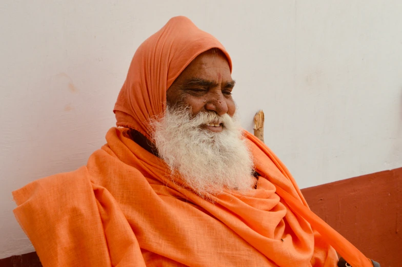 an old man wearing an orange outfit and with a beard