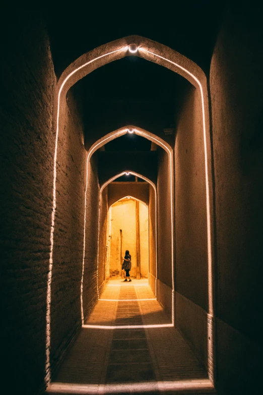 a tunnel lit up with white lights and a person on the end