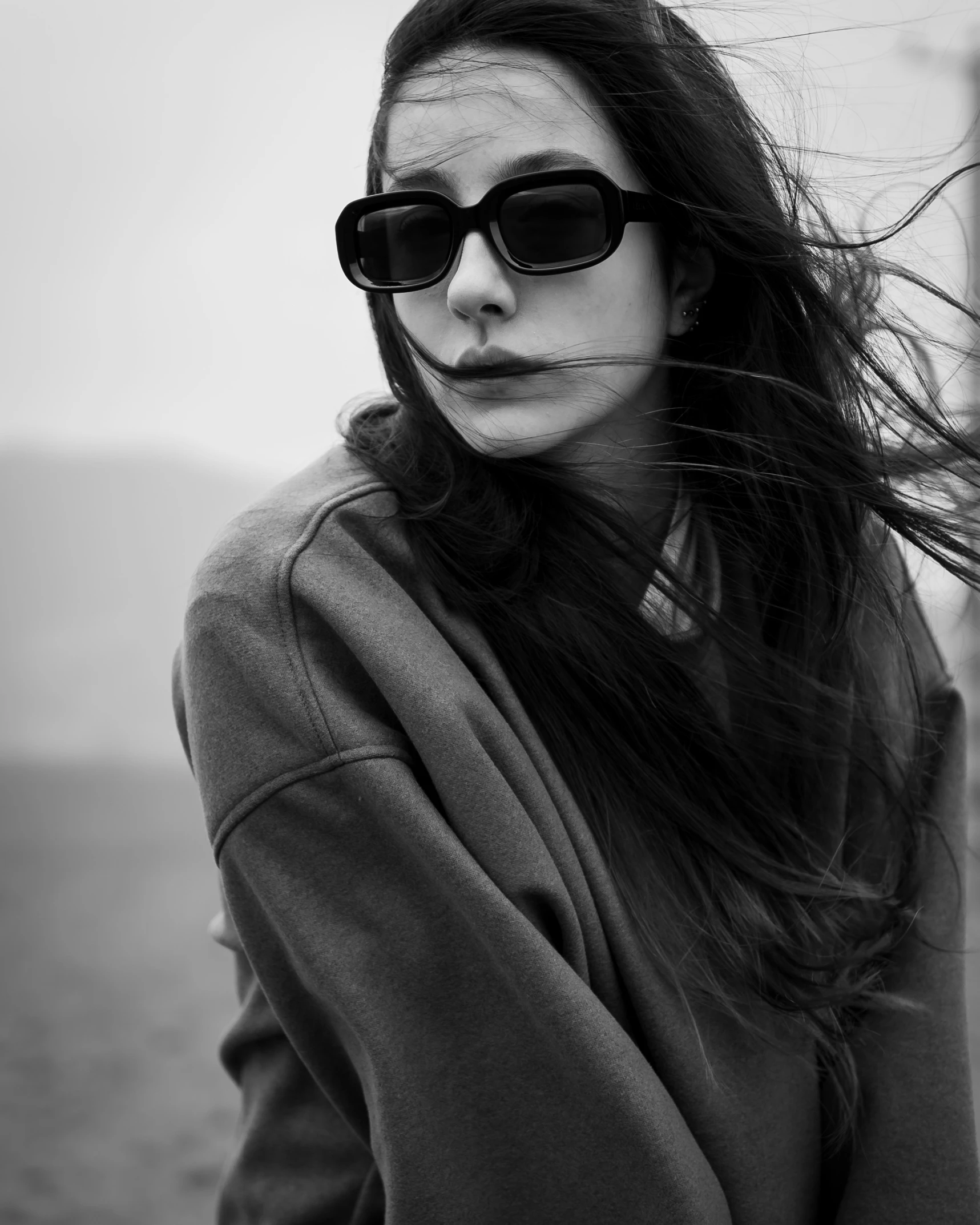 a woman wearing sunglasses is standing near a fence