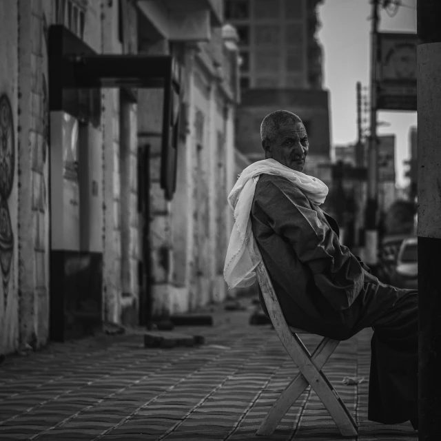 black and white pograph of a homeless man sitting on an urban chair