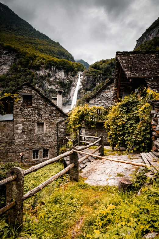 the building is made of stone with a waterfall running in the background