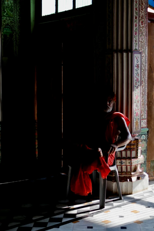 a woman in red is sitting down in a room