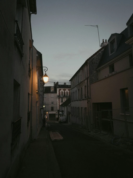 an alleyway at night with a lamp on the street next to it