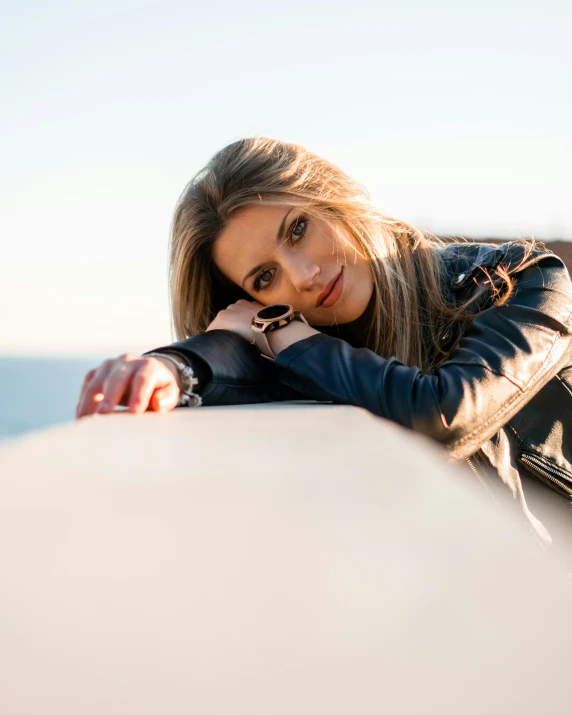 a young woman leans against the top of a wall