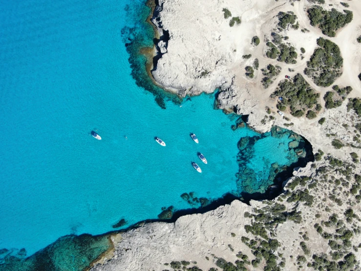 an aerial view of boats on clear blue water