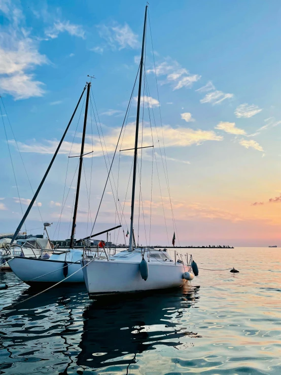 two sailboats on water near dock during sunset