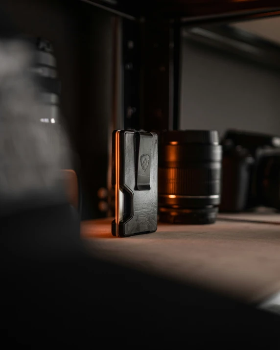 a black object sitting on a brown table next to some lens