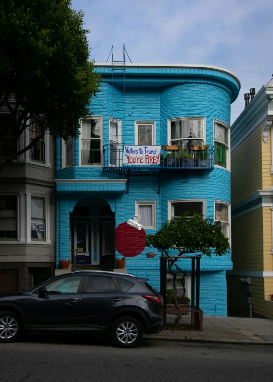 the car is parked next to the blue building