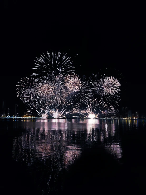 many fireworks are lit up over a body of water