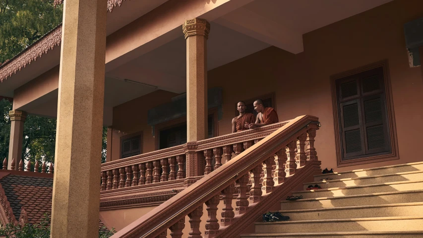 three people standing on a staircase in front of an elegant house