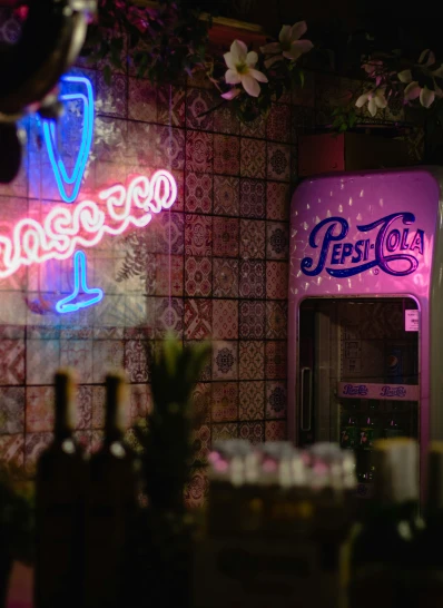 a neon pink pepsi cola sign sitting next to a wall