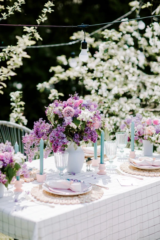 an outdoor table set up with plates and vases