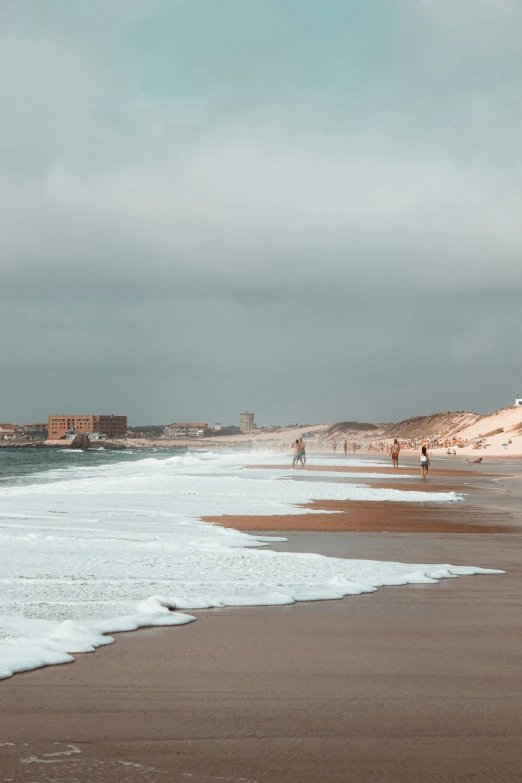 some people walking on a beach and some water