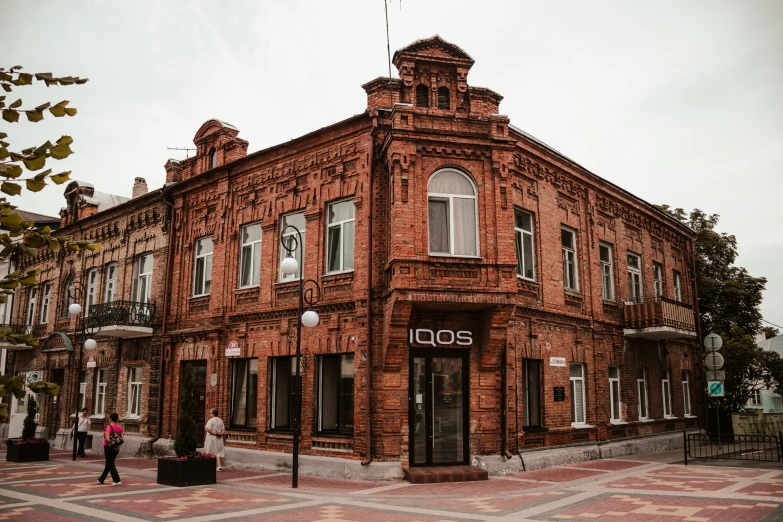 a brown building with some people and trees in the background