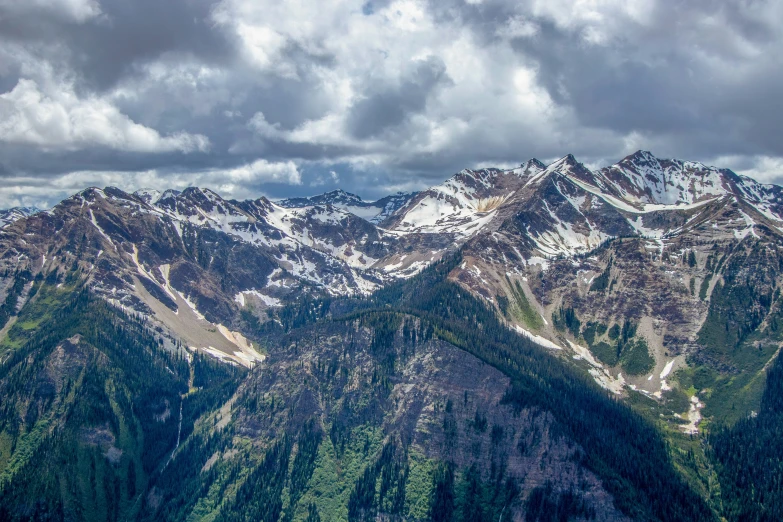 a mountain range with snow and trees below