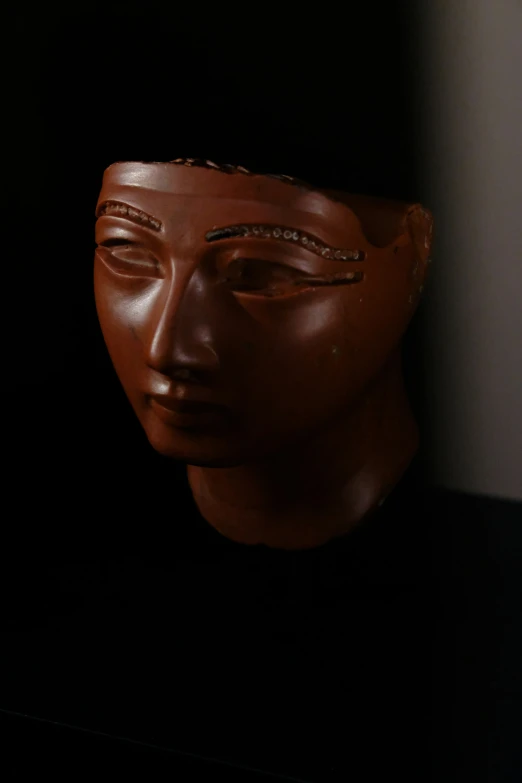 a clay head with eyes open on the black ground