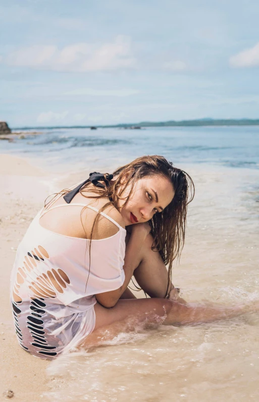 a woman in the sand wearing a bikini bottom