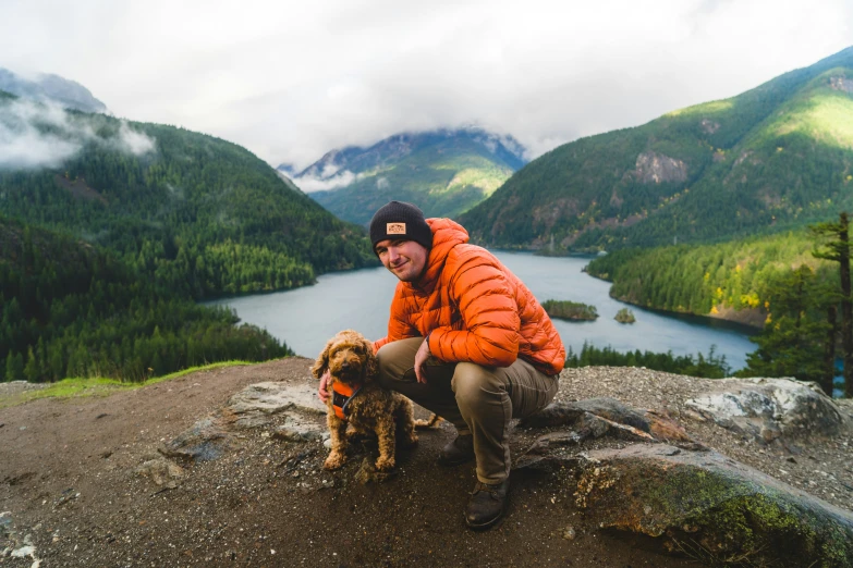 a man kneeling on top of a hill with a dog