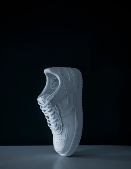 a white shoe is standing against a black background