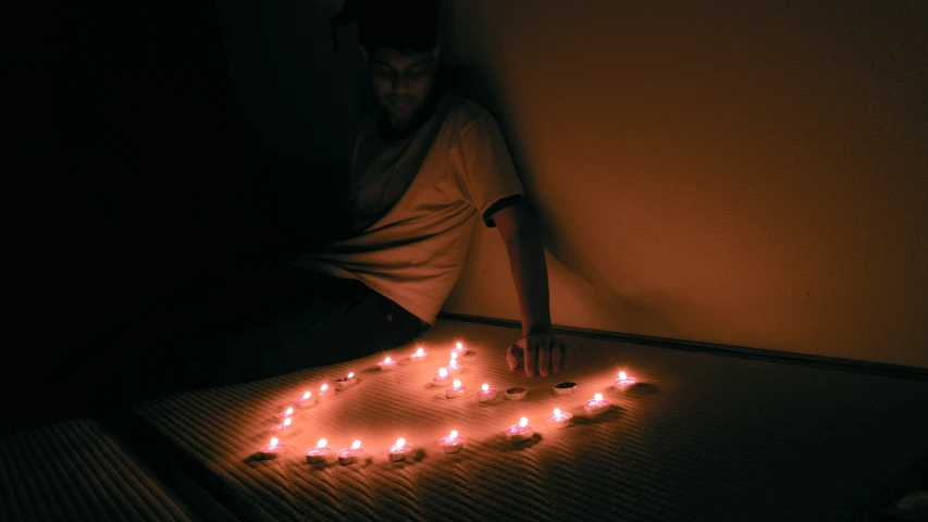 a man kneeling on the floor in front of a birthday cake that has lit candles