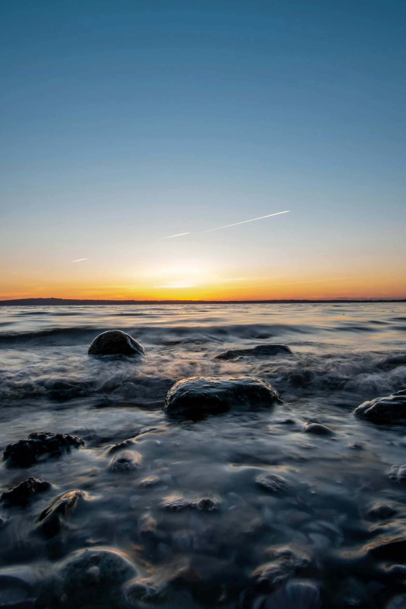 a sunset at the beach with lots of waves in the water