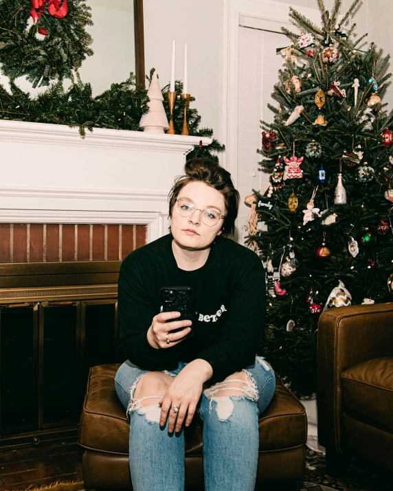 a woman sitting next to a christmas tree on a couch