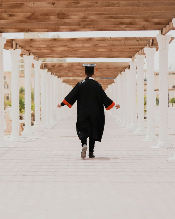 a man is walking down a pathway under some pillars