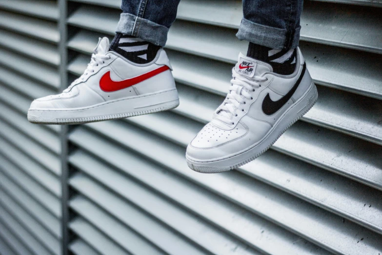 the nike air force one white and red is suspended over the wall