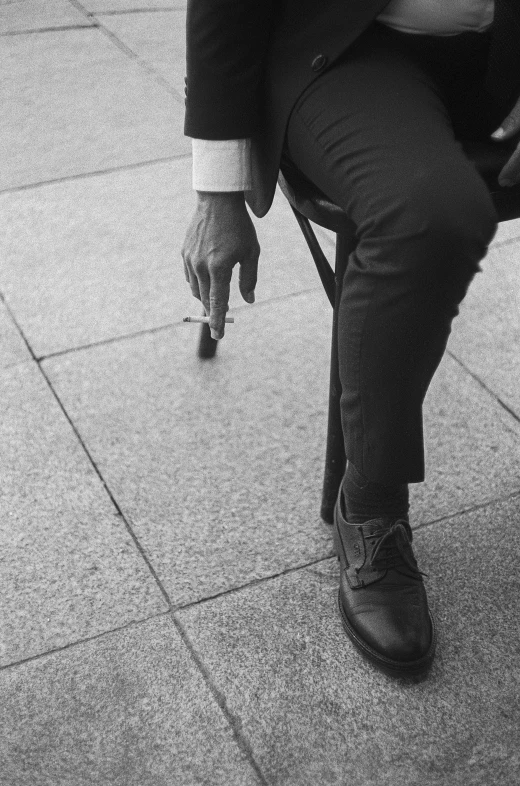 the person sits on a chair outside with their hand in his pocket