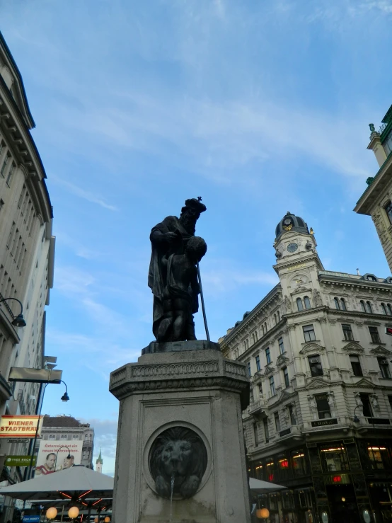 a statue of a person with a hat on it in the middle of a busy city