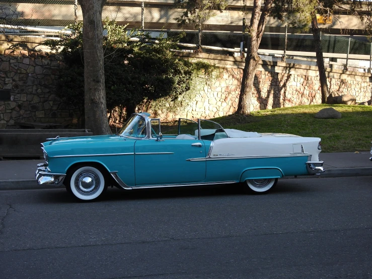 a blue classic car parked on the side of a road