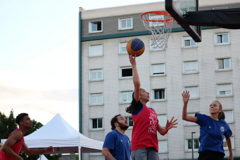 three basketball players, one reaching up to the basket and one in the air