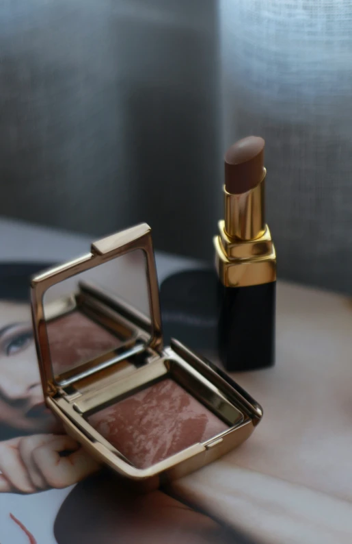 a closeup of a compact open makeup bag and a gold - toned compact container