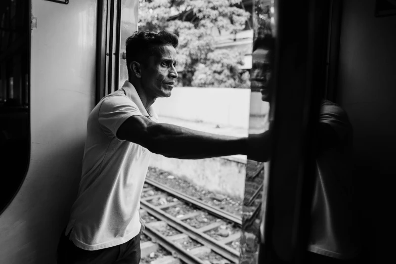 a man leaning against the window of a train