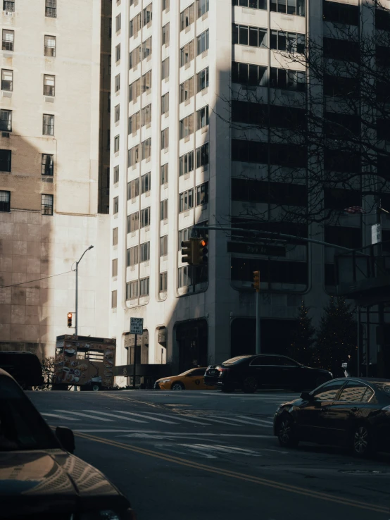 cars drive past an apartment building on the opposite side of the road