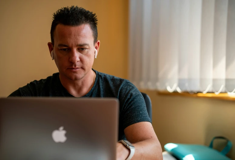 a man is sitting by himself on his macbook air