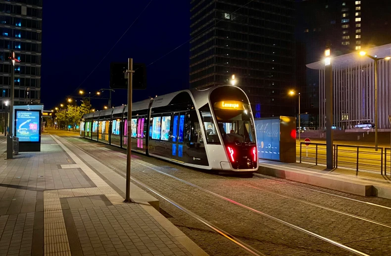 a public transit train on the tracks with buildings in the background