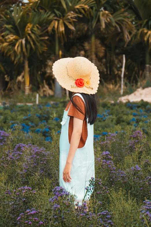 the woman wearing a sun hat walks in the field