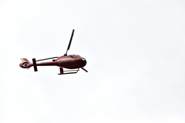 a red helicopter flying in a white sky