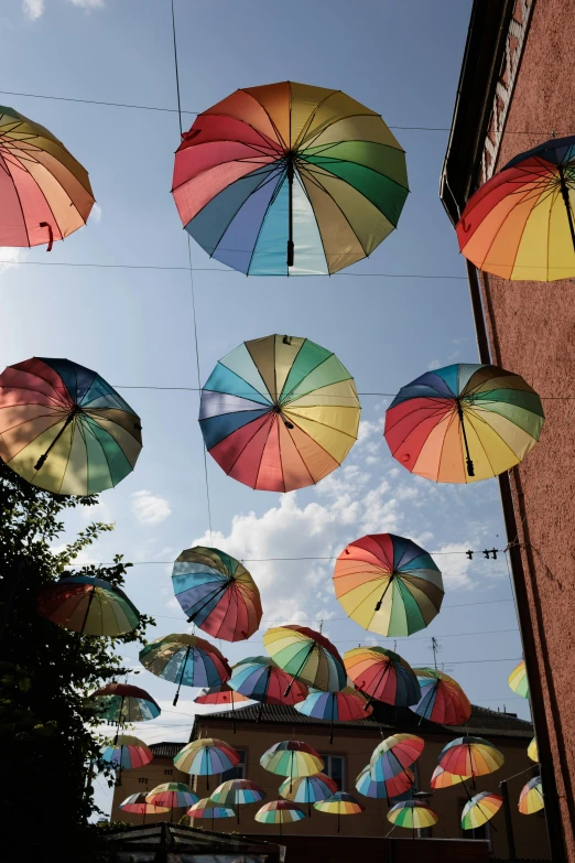 several rainbow umbrellas are flying in the air