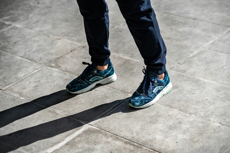 a person standing on a cement floor with tennis shoes