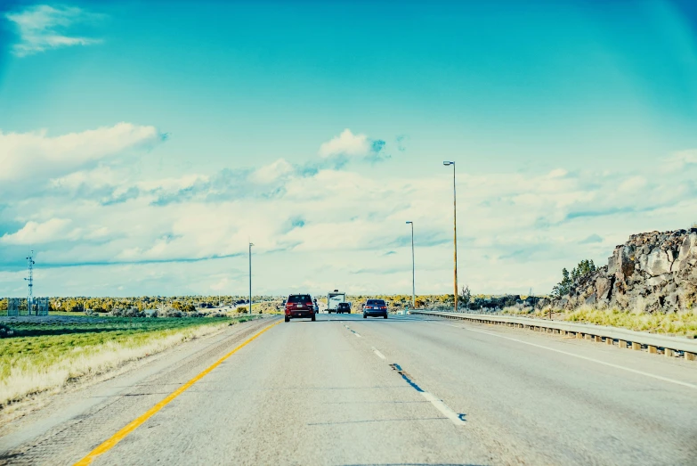 cars driving down an empty road under a blue sky