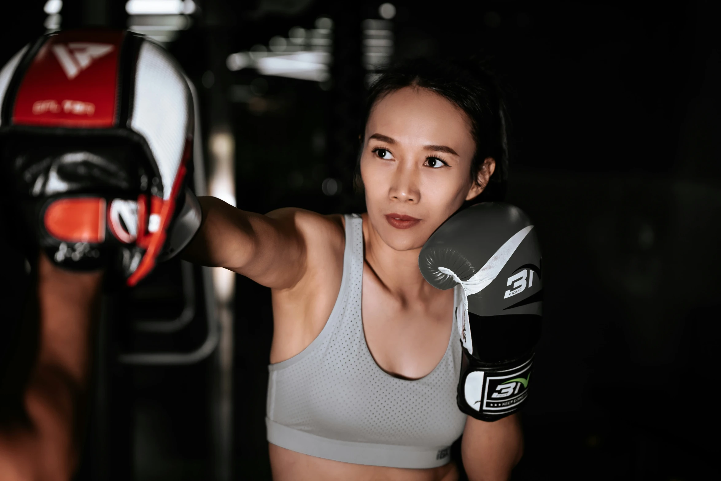 a beautiful woman in a grey top wearing boxing gloves