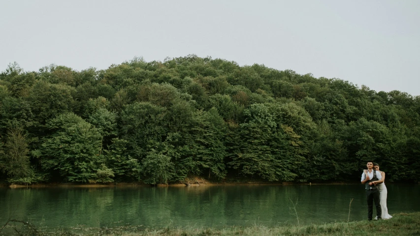 a person standing near some water near many trees