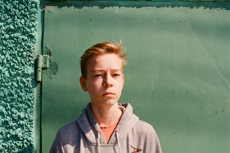 a young man posing for a picture in front of a green wall