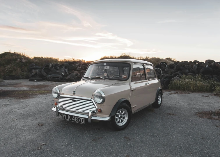 a small grey mini car parked in a gravel lot