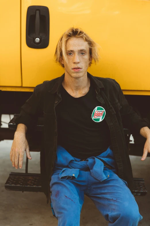 the man sits in front of a truck with the license plate of a motorcycle