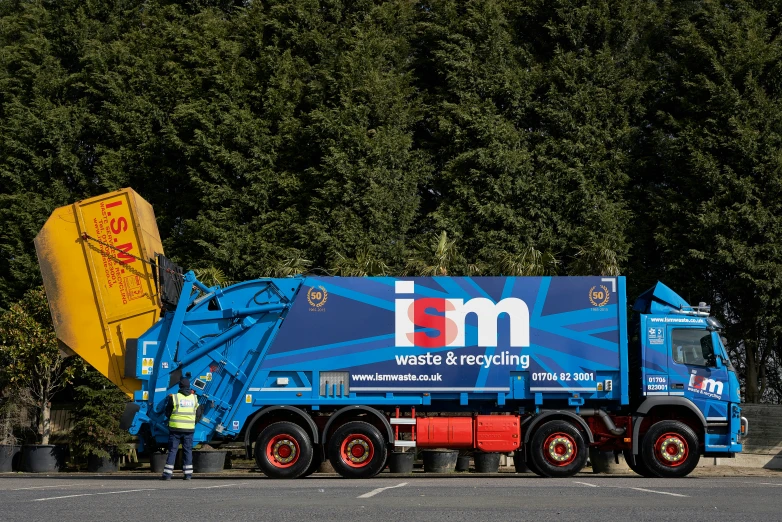 a garbage truck is parked in front of a group of trees