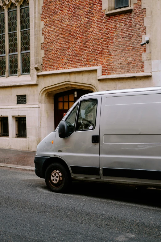 the van is driving down the street by the brick building