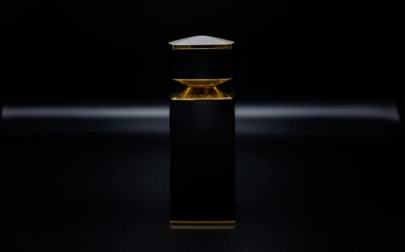 black cylinder with golden accents stands against a dark background